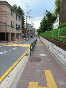 an empty city street with a sidewalk and yellow lines at A full private home in Seoul