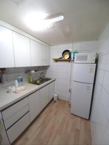 een keuken met witte kasten en een witte koelkast bij A full private home in Seoul