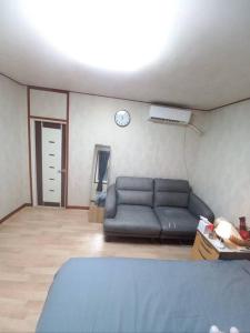 een woonkamer met een bank en een klok aan de muur bij A full private home in Seoul