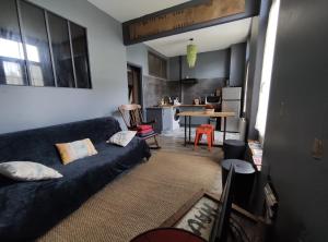 uma sala de estar com um sofá e uma cozinha em Numéro 12, appartement douillet em Montauban