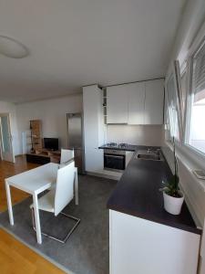 a kitchen with white cabinets and a white table and chair at Apartment City in Zagreb