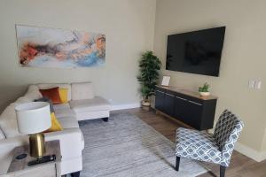 a living room with a white couch and a tv at Fully Furnished Alluring Turn Key Luxury Oasis in Wellington