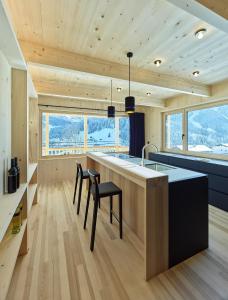 een keuken met een groot eiland met een wastafel en stoelen bij Tinn Naturchalet in Mittelberg
