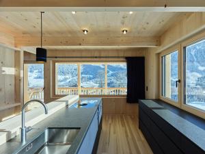 a kitchen with wooden walls and counters and windows at Tinn Naturchalet in Mittelberg