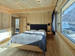 een slaapkamer met een bed en een groot raam bij Tinn Naturchalet in Mittelberg