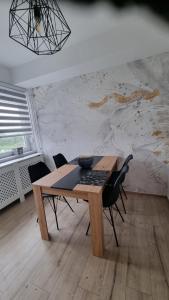 una mesa de madera y sillas en una habitación con pared en Apartman Nora, en Čakovec