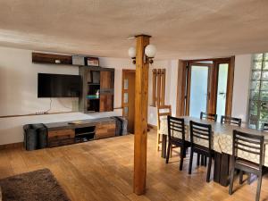 a dining room with a table with chairs and a television at Pensiunea Casa Madalina in Corbeni