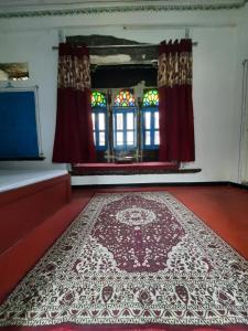 a room with a rug on the floor and windows at Madan Mohan Villas (A Haritage Haveli Home Stay) in Udaipur