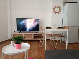 een woonkamer met een televisie en een tafel met stoelen bij Apartamento Happy Street in Socuéllamos