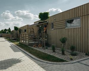 a wooden house with a patio and trees next to a sidewalk at MAZURY LAKE RESORT in Wydminy