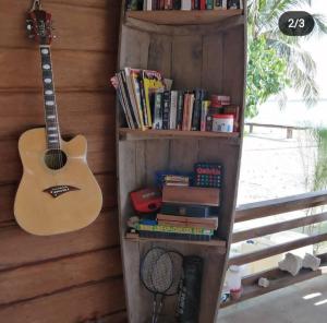 eine Gitarre und Bücher auf einem Bücherregal mit einer Gitarre in der Unterkunft Palambak Paradise Resort Pulau Banyak in Pulau Palambakbesar