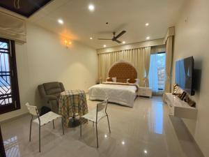 a bedroom with a bed and a tv and chairs at Blessing Mansion, Amritsar in Amritsar