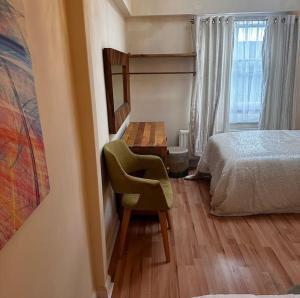 een slaapkamer met een bed, een stoel en een bureau bij Cosy Herne Bay Seaside Cottage in Kent