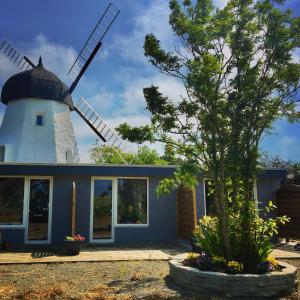 a house with a windmill in front of it at Apartamenty Molle in Åkirkeby