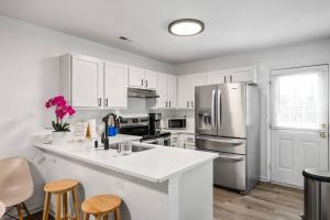 a kitchen with white cabinets and a stainless steel refrigerator at DT/2 Spacious 3BR Suites/FreeParking/SelfCheckin in Raleigh