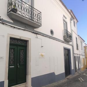 een wit gebouw met groene deuren en een balkon bij Patinha Inn in Évora