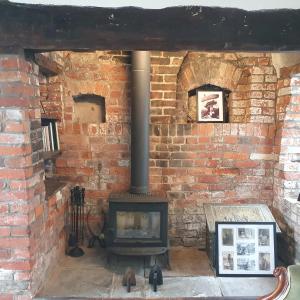 a brick wall with a stove in a room at Priory Cottage in Westbury