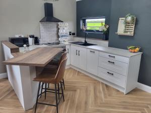 uma cozinha com armários brancos e uma mesa de madeira em Rose Meadow Lodge em Liscannor