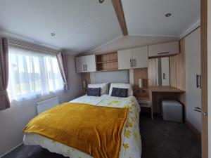 a bedroom with a bed with a yellow blanket on it at Polborder Holidays Looe Country Park in Looe