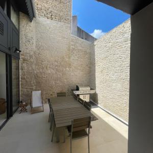 een kamer met een houten tafel en een bakstenen muur bij L'OCEAN a Oleron in Le Château-dʼOléron