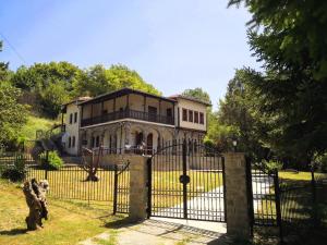 a house behind a gate with a dog in front at Zenios Dionysos - Traditional villa in Grevena