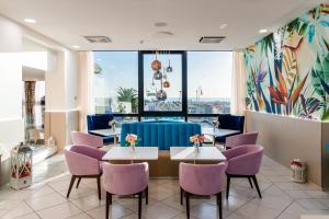 um restaurante com mesas e cadeiras roxas e uma grande janela em Hotel Ariane - BEACHFRONT, Breakfast XXL & Brunch em Rimini