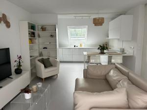 a white living room with a couch and a kitchen at Appartement Nuage blanc in Bitche