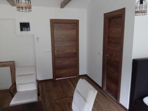 ein Wohnzimmer mit zwei Holztüren und einem weißen Stuhl in der Unterkunft Zicka plaza in Kraljevo