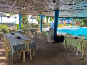 a patio with tables and chairs and a swimming pool at Camiguin Island Golden Sunset Beach Club in Mambajao
