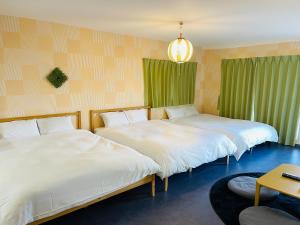 two beds in a room with green curtains at 心斎橋、道頓堀徒歩10分！難波、黒門市場、徒歩圏内の最高の立地 in Osaka