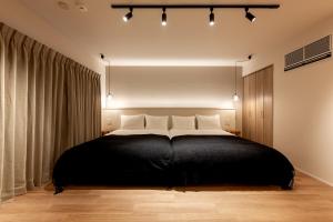 Un dormitorio con una gran cama negra con almohadas blancas en R.Kamakura en Kamakura