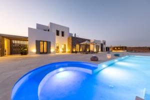 a large blue swimming pool in front of a house at Golden Bay luxury villas and suites in Chrissi Akti