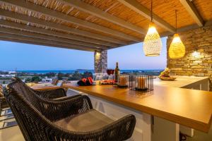 a kitchen with a bar with chairs and a view at Golden Bay luxury villas and suites in Chrissi Akti