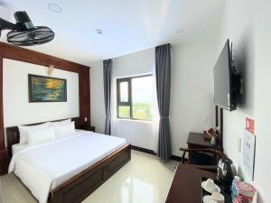 a hotel room with a bed and a television at Quang Hưng Hotel in Con Dao