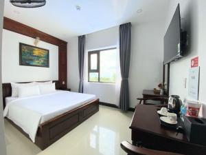een slaapkamer met een bed, een bureau en een televisie bij Quang Hưng Hotel in Con Dao