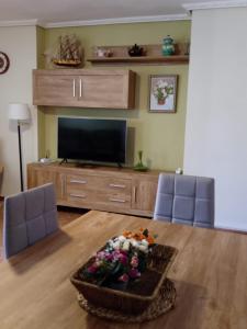 uma sala de estar com televisão e uma mesa com flores em Apartamento a 200m de Playa Morrongo em Benicarló
