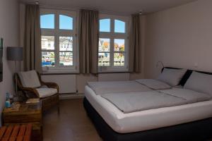 1 dormitorio con 1 cama, 1 silla y ventanas en Hotel Das Brückenhaus, en Glückstadt