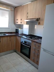 uma cozinha com armários de madeira, um fogão e um frigorífico em Apartamento a 200m de Playa Morrongo em Benicarló