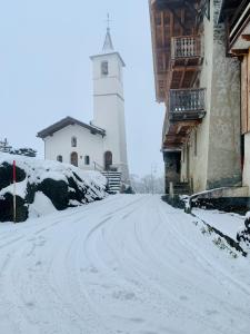 a snow covered street with a lighthouse in the background at Chalet Violettes in Villaroger