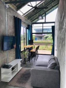 CMD 8 Hostel Success D Hostel Studio &CAFE’ في San Pa Tong: غرفة معيشة مع أريكة وطاولة مع كراسي