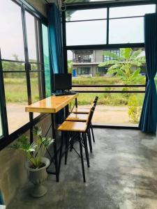 CMD 8 Hostel Success D Hostel Studio &CAFE’ في San Pa Tong: مكتب عليه كراسي وكمبيوتر في غرفة بها نوافذ