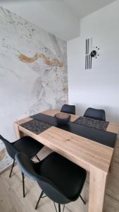 mesa de madera con 2 sillas negras y escritorio en Apartman Nora, en Čakovec