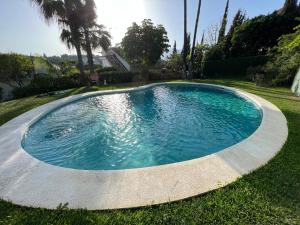 una piscina en un patio con césped y árboles en San Nicolas, en Marbella