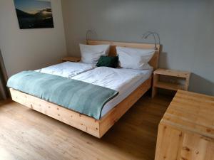 um quarto com uma cama de madeira com lençóis e almofadas brancos em Ferienwohnung Frech em Thaur
