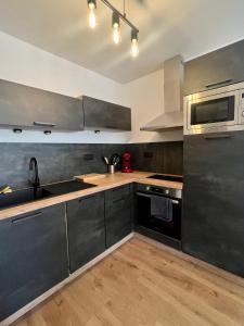 cocina con electrodomésticos de acero inoxidable y suelo de madera en Agréable T2 idéalement situé en Mende