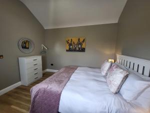 a bedroom with a large white bed and a dresser at Rose Meadow Lodge in Liscannor