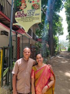 un hombre y una mujer parados frente a un edificio en Wild Window - Forest View Homestay, en Thekkady