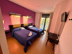 2 Betten in einem Zimmer mit lila Wänden in der Unterkunft HOSTAL RESTAURANTE AQUA in Ourense