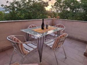 una mesa de cristal con una botella de vino y 4 sillas en Apartman Flavio, en Skrbčići