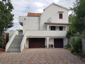 una gran casa blanca con entrada y escaleras en Apartman Flavio, en Skrbčići